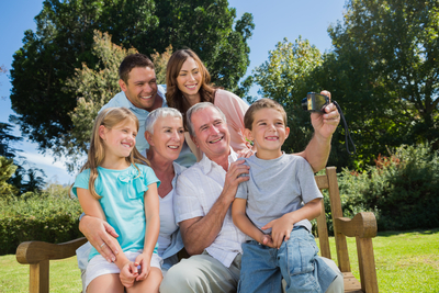 Multi generation family sitting on a bench taking photo of themselves